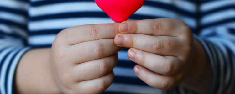 a small pink heart being held by a small child