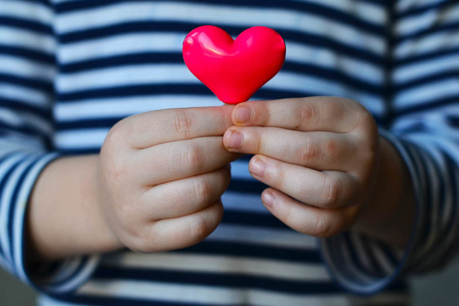 a small pink heart being held by a small child